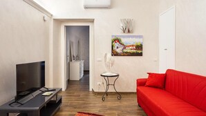 A modern living room with a red sofa, a TV, and a small table with decorative items. - 2 bedroom apartment in rome (Roma)