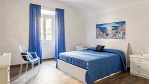 A bedroom with a bed, a chair, a nightstand, and a painting on the wall. - 2 bedroom apartment in rome (Roma)