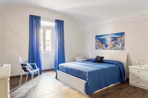 A bedroom with a bed, a chair, a nightstand, and a painting on the wall. - 2 bedroom apartment in rome (Roma)
