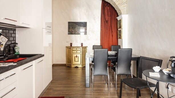 A compact kitchen with white cabinets, a black countertop, and a red curtain. - 2 bedroom apartment in rome (Roma)
