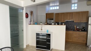 A modern kitchen with wooden cabinets, a white countertop, and a black refrigerator.