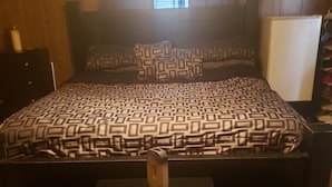 Un dormitorio con cama, mesita de noche, cómoda y ventana con persianas.