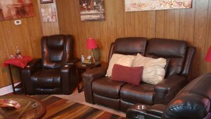 Una sala de estar con sofás de cuero, una mesa de centro de vidrio y paneles de madera.