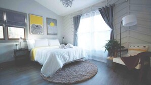 A bedroom with a bed, a round rug, a chair, a plant, and artwork on the wall. - Luxe Bungalow in Downtown Decatur / 2BD 2 BA (Decatur)