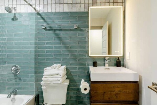 A bathroom with a white sink, a mirror, and a toilet. - Luxe Bungalow in Downtown Decatur / 2BD 2 BA (Decatur)