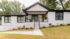 A modern two-story house with a covered porch, a front yard, and a small garden. - Luxe Bungalow in Downtown Decatur / 2BD 2 BA (Decatur)