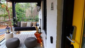 A covered outdoor seating area with a bench, ottomans, and lanterns. - Luxe Bungalow in Downtown Decatur / 2BD 2 BA (Decatur)