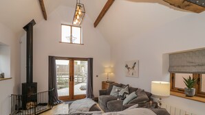 A cozy living room with a fireplace, a sofa set, and a window with a view of the outside. - The Parlour (Droitwich)