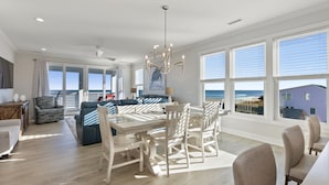 A spacious living area with a dining table, chairs, and a view of the ocean. - Enjoy AMAZING VIEWS at almost new spacious oceanfront unit, huge deck, elevator (Carolina Beach)