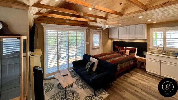 Un dormitorio acogedor de estilo cabaña con una cama grande, una zona de estar con sofá y una kitchenette.