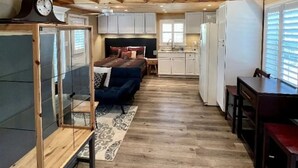 Un espacio habitable compacto y de planta abierta con techo de madera, ventilador de techo, cama, kitchenette y comedor.