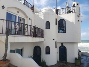 Un edificio blanco con balcones, ventanas arqueadas y una puerta.