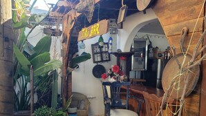 A rustic tiki bar with wooden furniture, a stone floor, and tropical plants.