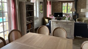 Un soggiorno accogliente con camino, televisore e zona pranzo con sedie in vimini.