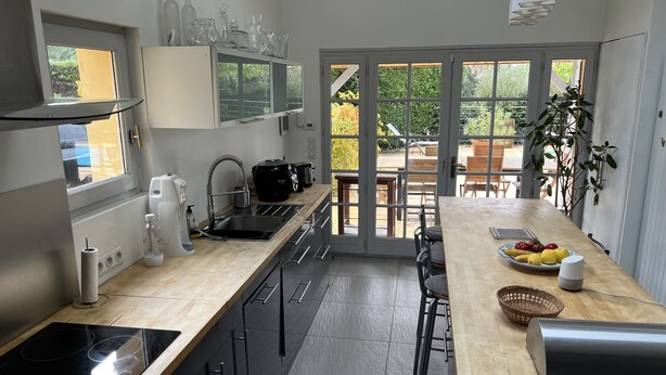 Una cucina moderna con una grande isola, forno integrato e zona pranzo con vista sul giardino.