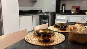 A modern kitchen with white cabinets, a black countertop, and a microwave. - Melhores Flats (Cabedelo)