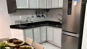 A modern kitchen with a black countertop, white cabinets, and a stainless steel refrigerator. - Melhores Flats (Cabedelo)