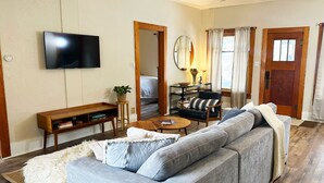 A living room with a grey sofa, wooden coffee table, and a flat-screen TV mounted on the wall. - Sunny Downtown Gunnison Retreat (Gunnison)