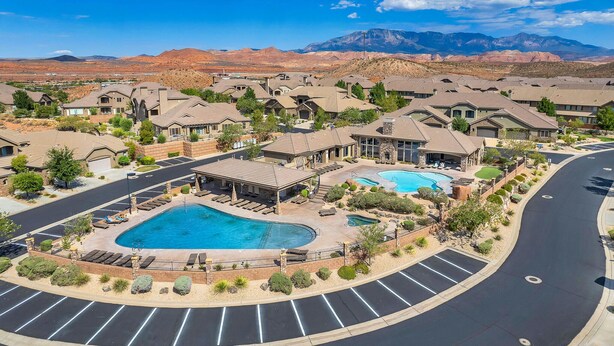 A residential area with multiple houses, a swimming pool, and a mountain range in the background. - Spacious, Clean Coral Ridge Townhome (Washington)
