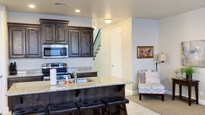 A modern kitchen with dark wood cabinets, a granite countertop, and a bar area with stools. - Spacious, Clean Coral Ridge Townhome (Washington)