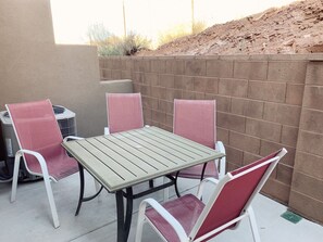 A patio with a table and four chairs, a brick wall, and a small pile of dirt in the background. - Spacious, Clean Coral Ridge Townhome (Washington)