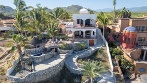 A resort with a central building surrounded by a landscaped area with palm trees and a stone pathway.