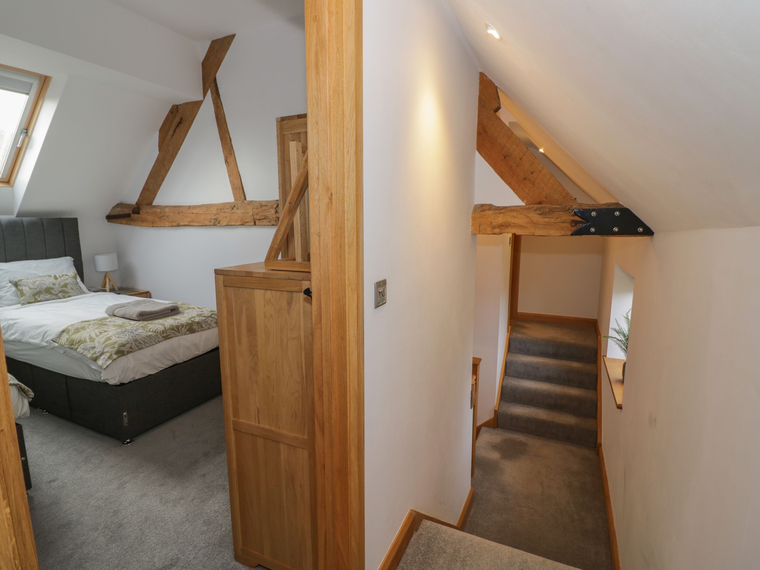 Une chambre à coucher avec un lit, une armoire en bois et un escalier.