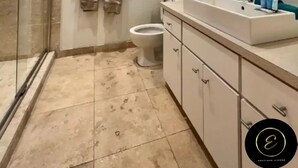 Ein modernes Badezimmer mit Duschkabine aus Glas, Toilette, Waschbecken mit Spiegel und Fenster mit Jalousien.