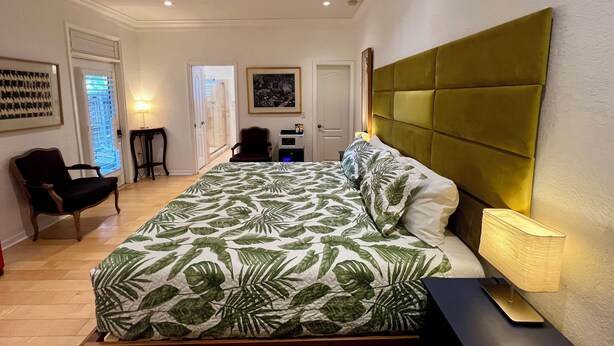 Ein Schlafzimmer mit Bett, Deckenventilator, Schreibtisch, Stuhl und einer Tür.