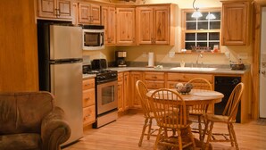 A kitchen with wooden cabinets, a refrigerator, stove, and a dining table with chairs.