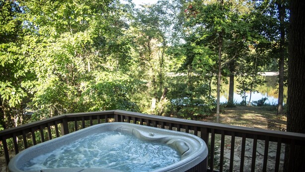 A hot tub on a wooden deck with a view of a lake and trees. - Hot Tub Cabin- In the Heart of Shawnee Wine Trail (Carbondale)