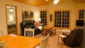 A cozy living room with a wooden ceiling, a leather sofa, a dining table, and a TV. - Hot Tub Cabin- In the Heart of Shawnee Wine Trail (Carbondale)
