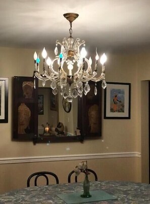 Enjoy meals in this elegant dining area with a large chandelier, marble table, and comfortable seating.