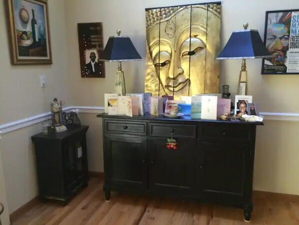 Cozy room features a cabinet with drawers and a small compartment, topped with decorative items and artwork.