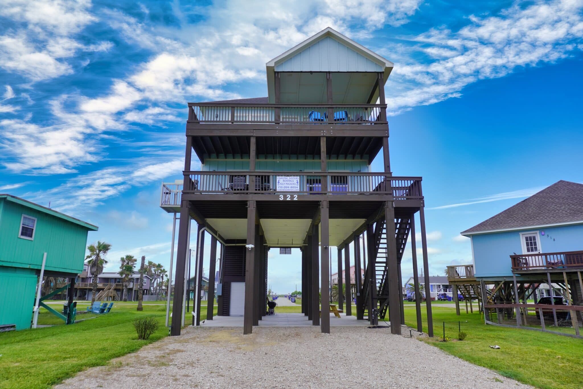 A multi-level wooden structure with balconies, a covered walkway, and a clear view of the beach.