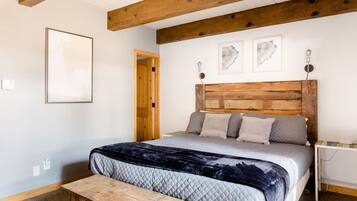A bedroom with a wooden headboard, a bed with a quilted cover, a bench, and framed artwork on the wall.
