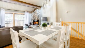 Un salon chaleureux avec une cheminée, des meubles blancs et un mur d’accent en pierre.