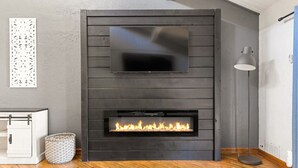 A modern living room with a fireplace, a mounted TV, and a floor lamp.