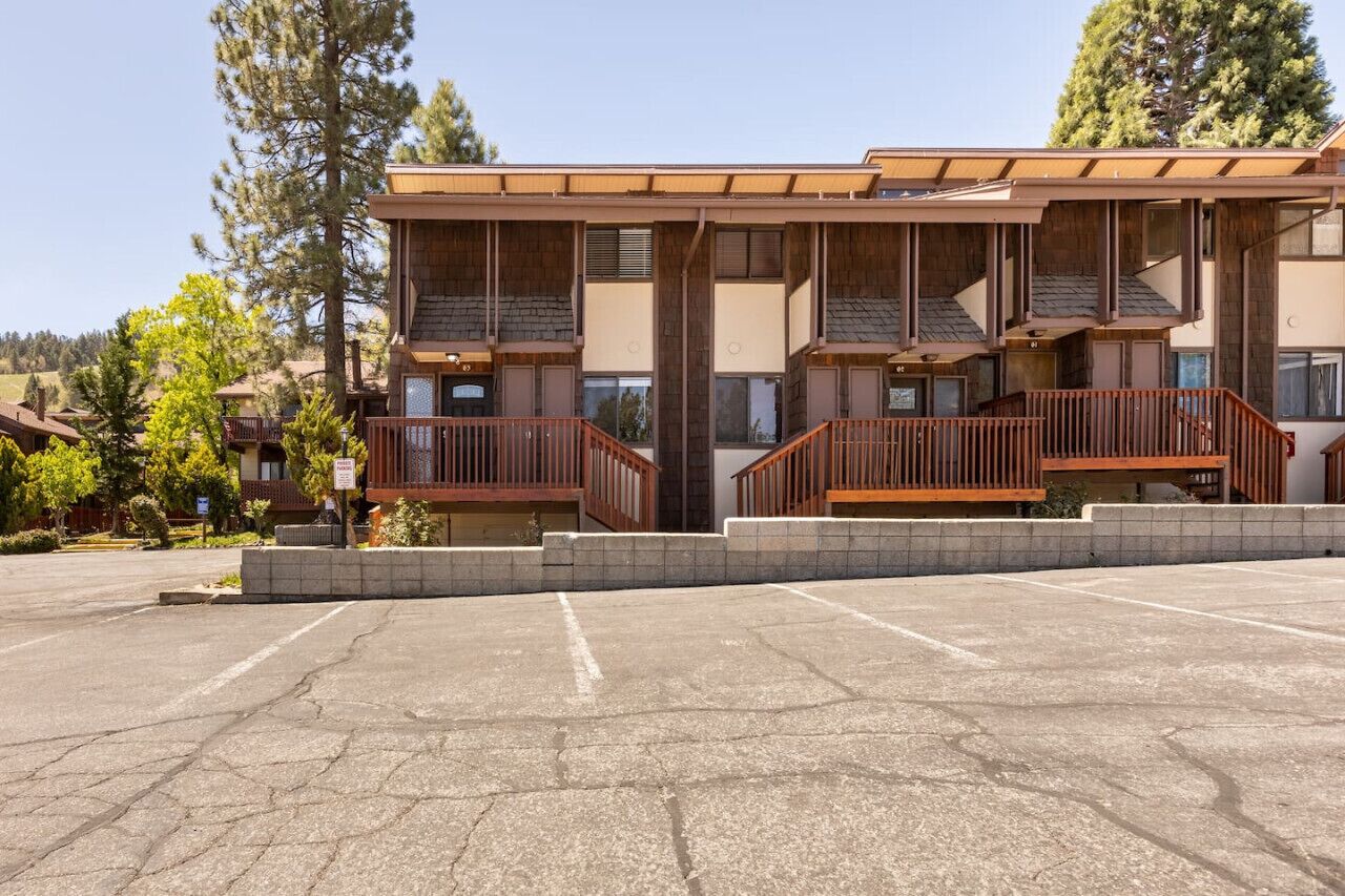 A multi-story building with a wooden facade, balconies, and a parking lot.