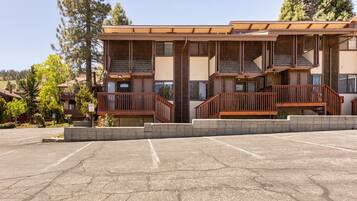 A multi-story building with a wooden facade, balconies, and a parking lot.