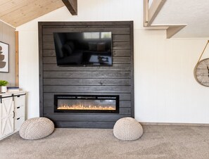Una sala de estar moderna con chimenea, un televisor montado y un reloj en la pared.