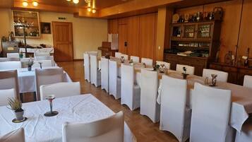 Un área de comedor con varias mesas y sillas, cada una cubierta con manteles blancos.