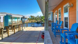A waterfront property with wooden deck chairs, a covered area, and a view of the water. - Captain Twig by Avantstay Getaway 3 Blocks From Beach (Port Aransas)