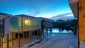 A waterfront property with multiple wooden structures, a dock, and a calm lake. - Captain Twig by Avantstay Getaway 3 Blocks From Beach (Port Aransas)