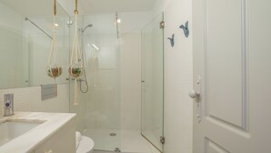 Ein modernes Badezimmer mit Duschkabine aus Glas, einem weißen Waschbecken und einer Toilette.