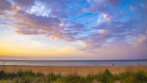 A beach with a clear sky and a few people walking. - Beachfront Getaway, pet friendly (Norfolk)