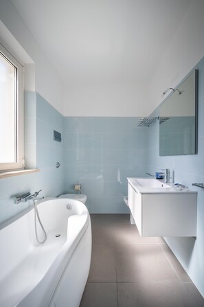 A modern bathroom with a bathtub, toilet, and vanity.