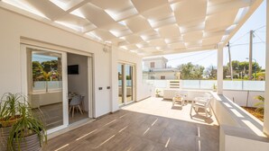 Un vaste espace patio agrémenté d’une pergola, d’une table à manger avec des chaises et d’une plante en pot.