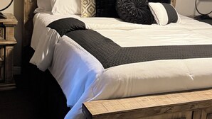 A bed with a wooden headboard, multiple pillows, and a white comforter. - Sylvia’s Getaway
 (Longview)
