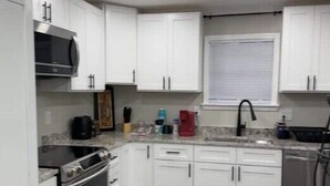 A modern kitchen with white cabinets, stainless steel appliances, and a granite countertop. - Sylvia’s Getaway
 (Longview)